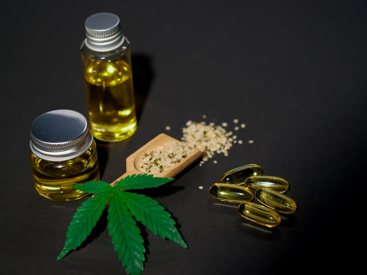 High-quality image featuring cannabis oil, seeds, leaves, and capsules on a dark background.